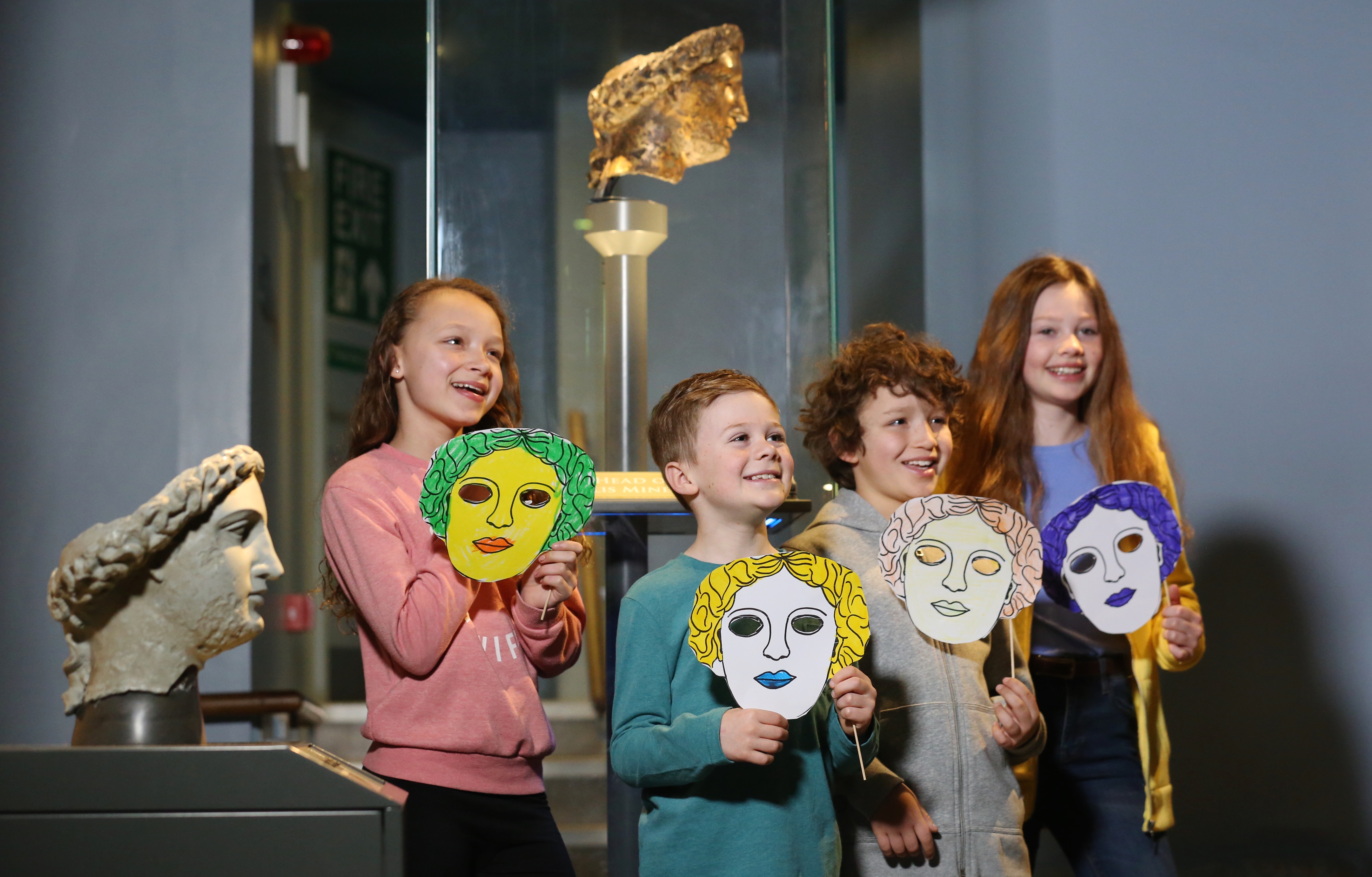 Image: Children standing in front of Minerva's head with masks they've made
