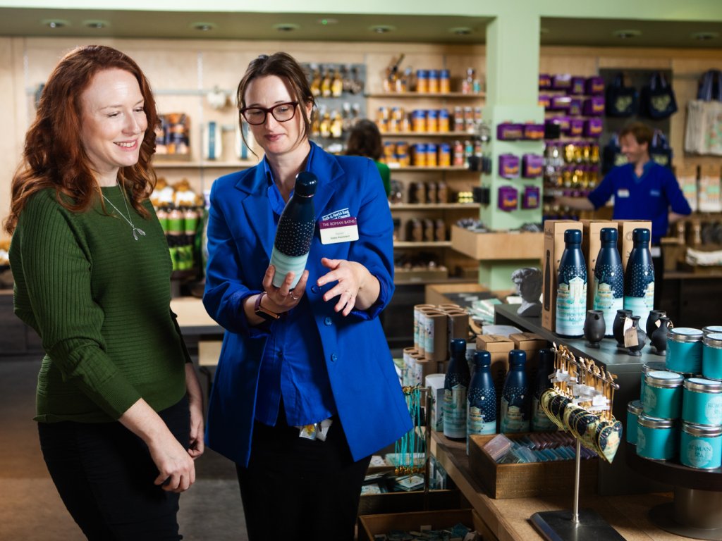 Image: A sales assistant showing a visitor a water bottle