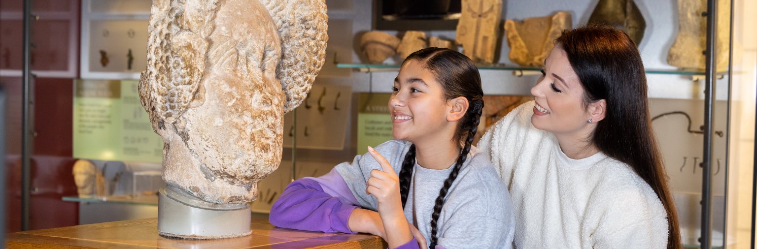 Visitors looking at a Roman artefact in the museum